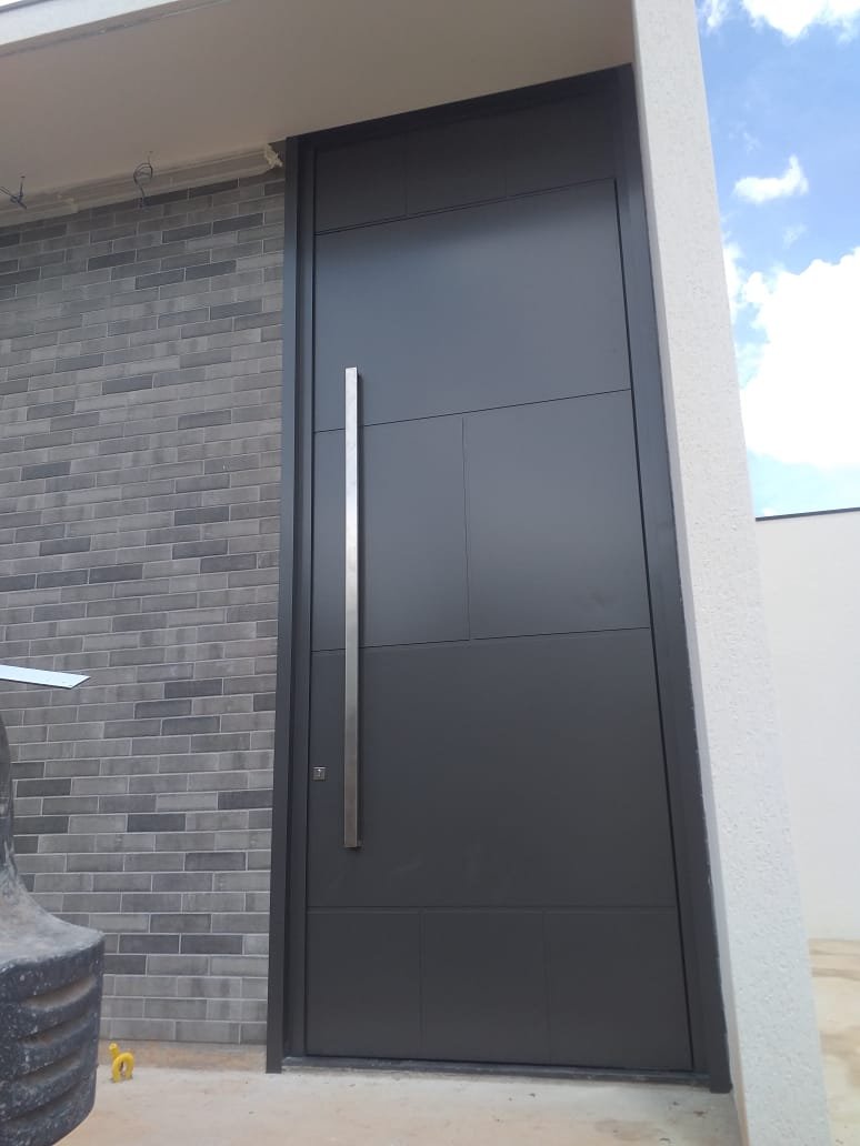 Porta pivotante em ACM grafite fosco instalada em fachada residencial